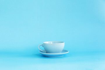 Blue cup and saucer on a blue background side view.