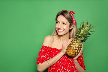 Young woman with fresh pineapple on green background, space for text. Exotic fruit