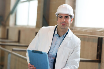 man in a lab coat and helmet in factory