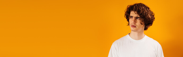 Fototapeta premium Offended man looking away isolated on orange, banner