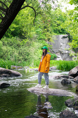 hiker woman in yellow raincoat enjoying view of river in canyon