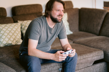 Mann spielt im Wohnzimmer ein Computerspiel mit einem Controller