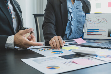 hand holding pen, businesswomen and businessmen team meeting to plan strategies to increase business income. Have a brainstorming finance graph analysis and discussing for the new target success