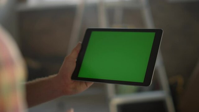 Woman hand touching green screen. Unknown girl working on tablet indoors.