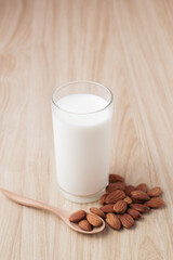 almond milk in glass on wood background with nuts around the bowl.selective focus.front view.copy space.