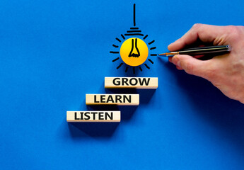 Listen, learn, grow symbol. Wooden blocks with concept words listen, learn, grow. Blue background. Businessman hand, light bulb icon. Copy space. Business, educational and listen, learn, grow concept.