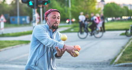 A juggler working in traffic. 
Juggler man performing at the traffic lights, after the presentation...
