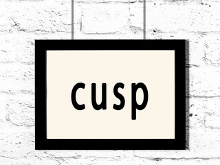Black frame hanging on white brick wall with inscription cusp