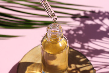 Bottle of cosmetic essential oil with dropper on a wood cut close-up. Serum oil is dripping from...