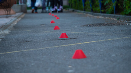 Children skates on asphalt and goes round cones