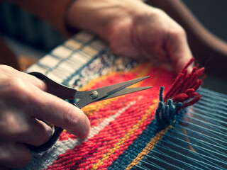 Master weaver is cutting the ends of the threads to create a cut pile carpet effect. Making...
