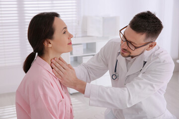 Doctor examining thyroid gland of patient in hospital - obrazy, fototapety, plakaty