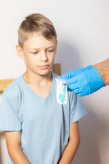 hands of a nurse in blue gloves open a pack of syringe close-up in front of the face of a boy in a blue t-shirt