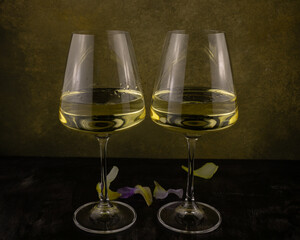 a glass of white wine and gladiolus petals