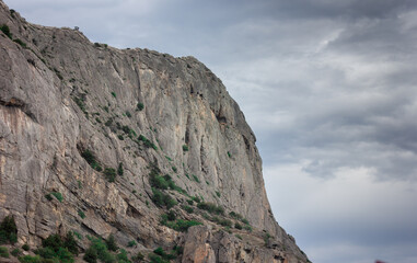 A rock on the seashore. The coastline. A mountain sticking out of the sea.