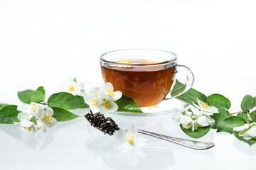 Glass cup with jasmine green tea on a white background with reflection and shadows. Decorated with...