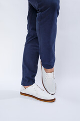 Fototapeta na wymiar Men's feet in white everyday sneakers made of natural leather on lacing.