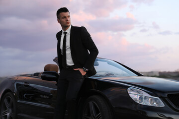 Handsome businessman near luxury convertible car outdoors