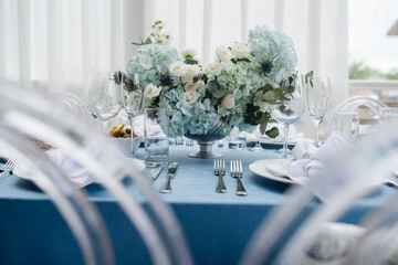 Luxurious round table set for an event, decorated with lush blue bouquets