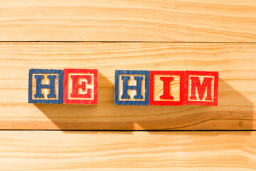 Spectacular wooden cubes with the word HE HIM on a wooden surface. - obrazy, fototapety, plakaty