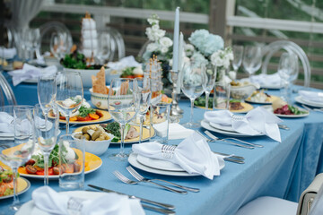 Two tables setting for an event on a terrace. Empty plates with napkins