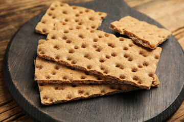 Board with fresh rye crispbreads on wooden table, closeup