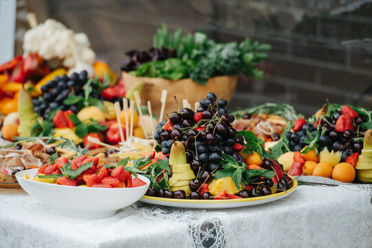 Low angle image of an abandant table set for event. Large plates full of fruit.