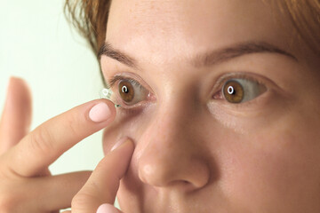 A young woman inserts lenses into her right eye