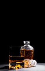 Close-up of a crystal glass along with a bottle full of whiskey on black background.