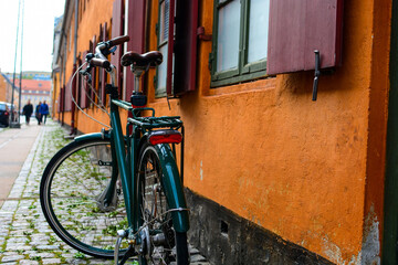 Bicycle with basket in front of the orange wall in Copenhagen, Denmark. Colorful old town architecture and eco friendly transport. Copenhagen style, European street, Denmark bicycle