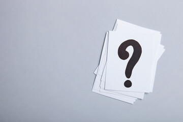 Paper cards with question marks on grey background. Pile of question marks, top view with place for...