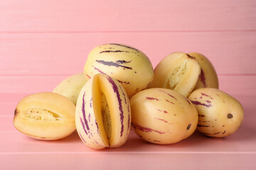 Whole and cut pepino melons on pink wooden table