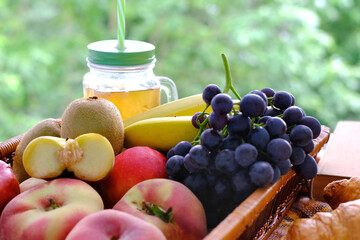 beautiful summer still life, fruits, grapes, peaches, apples, croissants, green trees in the background, concept picnic in nature, summer vacation, healthy eating