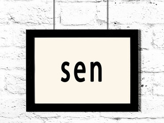 Black frame hanging on white brick wall with inscription sen © iushakovsky