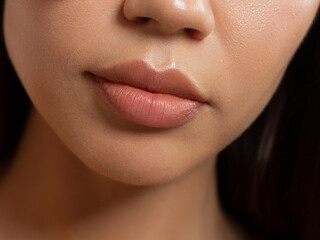 Obraz premium Cosmetics, makeup and trends. Bright lip gloss and lipstick on lips. Closeup of beautiful female mouth with natural lip makeup. Beautiful part of female face. Perfect clean skin in red light
