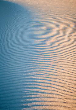 light and pattern on wave shapes at white sand dune at sunset