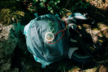 compass backpack and hiking boots on the ground in the wild