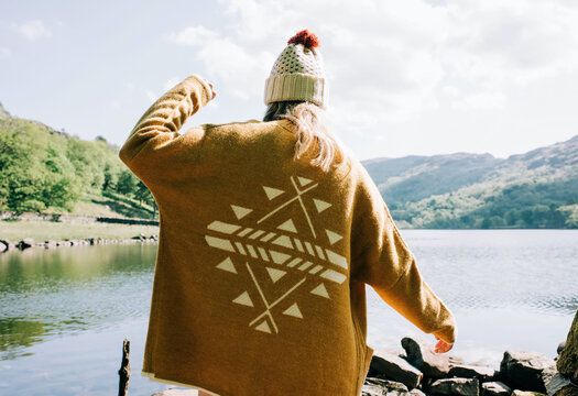 woman wearing aztec cardigan walking by the lake and mountains