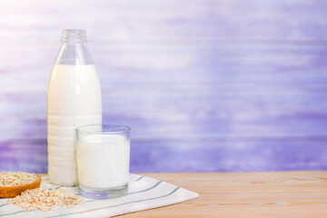 glass of milk, bottle with milk and oatmeal on a blue wooden background