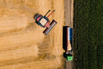 Aerial shot of combine loading off wheat grains into truck trailer. from above. 4K footage in a...