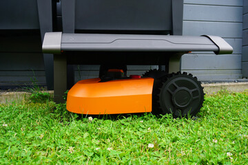 Ein Mähroboter steht auf dem Rasen unter seiner Garage