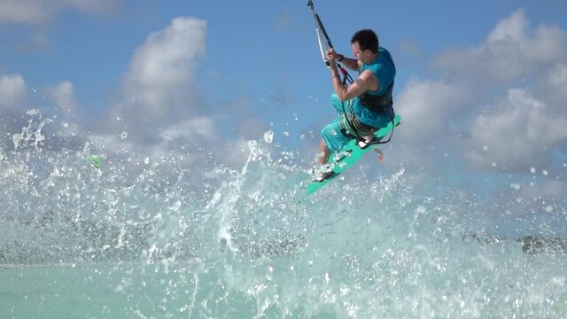 SLOW MOTION: Kitesurfer attempting a trick crashes into the spectacular turquoise ocean water while riding in windy Zanzibar. Funny shot of a male tourist failing while kiteboarding in Tanzania.