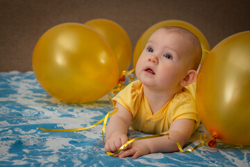 A small child in a yellow dress in the middle of yellow inflatable balloons