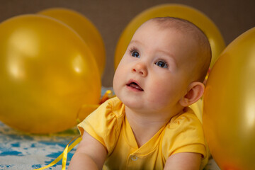 A small child in a yellow dress in the middle of yellow inflatable balloons