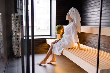 A woman is sitting warming herself in a sauna. Detox program spa self-care. girls with a towel on...