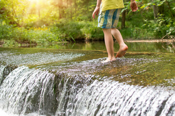 Kids legs walkingin watere  in stream in the summer. Outdoor, barefoot, holiday concept