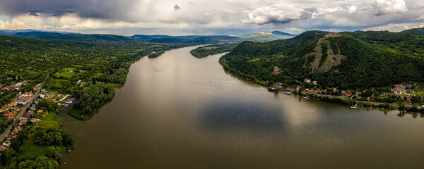 Aerial panorama view of the Danube river at Danube bend. There is the city of Visegrad and the Upper Castle of Visegrad on the right and there is the city of Nagymaros on the left side.