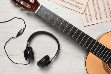 Naklejka premium Composition with guitar and music notations on light wooden table, flat lay