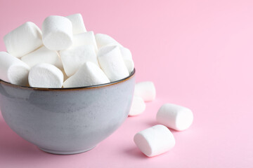 Fototapeta na wymiar Delicious puffy marshmallows on pink background, closeup. Space for text