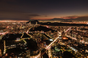 Aerial view of a sunset in Santiago de Chile with its buildings and streets illuminated and the mountains outlined in the background.